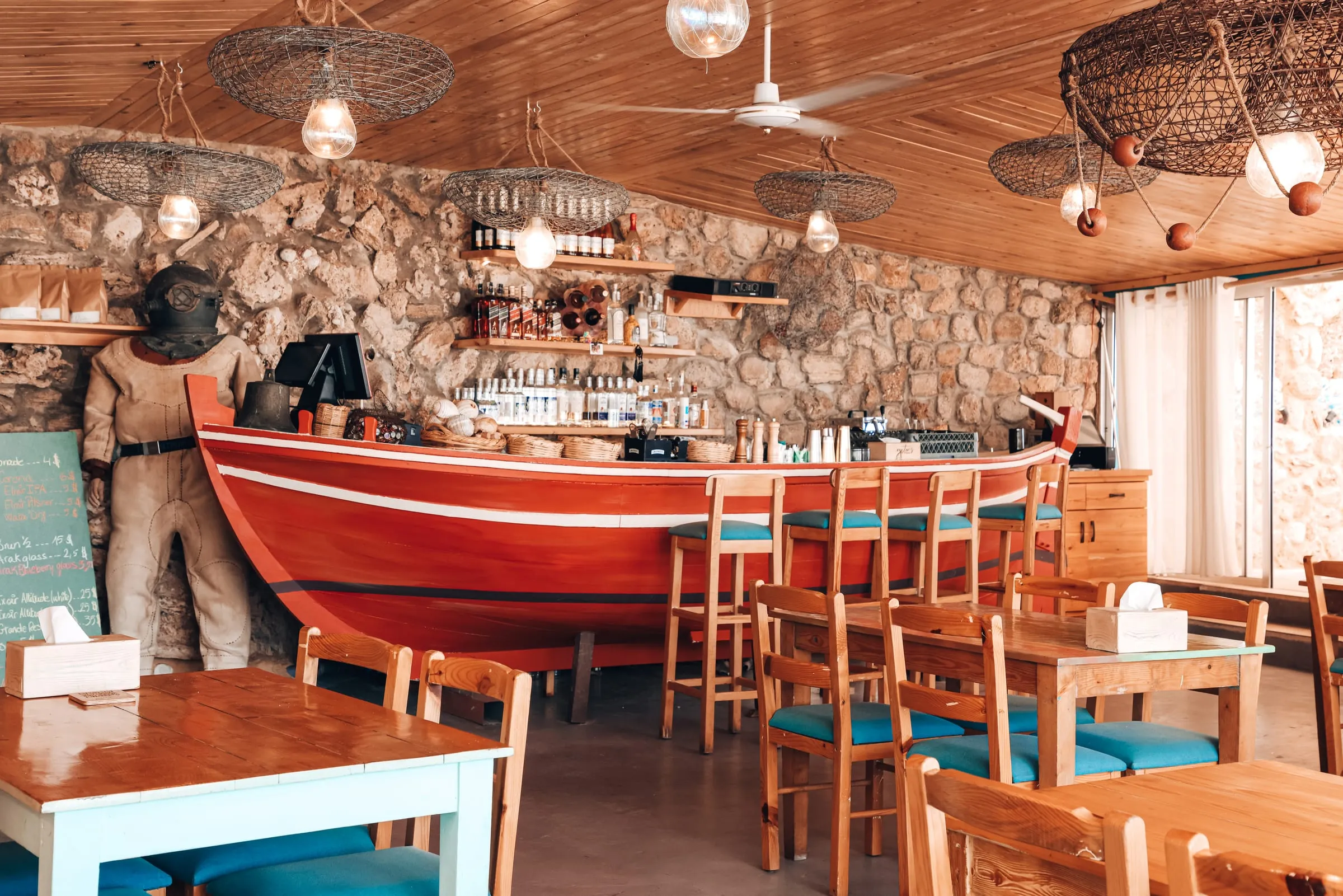 The dining room at Oyster's Seafood Bar, Batroun: a red wooden boat as the bar, stone walls and fish-trap lamps