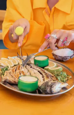 A whole grilled fish being squeezed with lemon by a guest at Oyster's Seafood Bar, Batroun