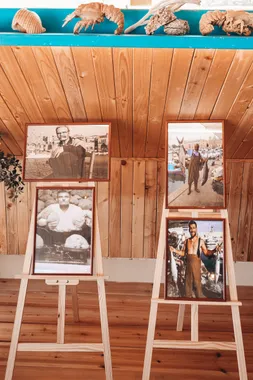 Black and white portraits of Batroun fishermen on easels against a wooden wall at Oyster's Seafood Bar
